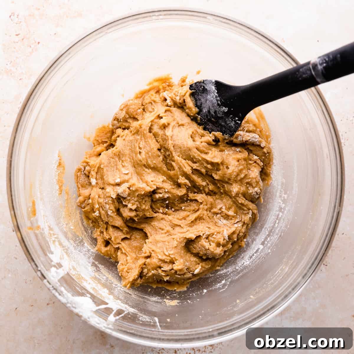 Butterscotch Chocolate Chip Cookie Recipe 5 glass bowl with plain cookie dough and black silicone spatula inside it.