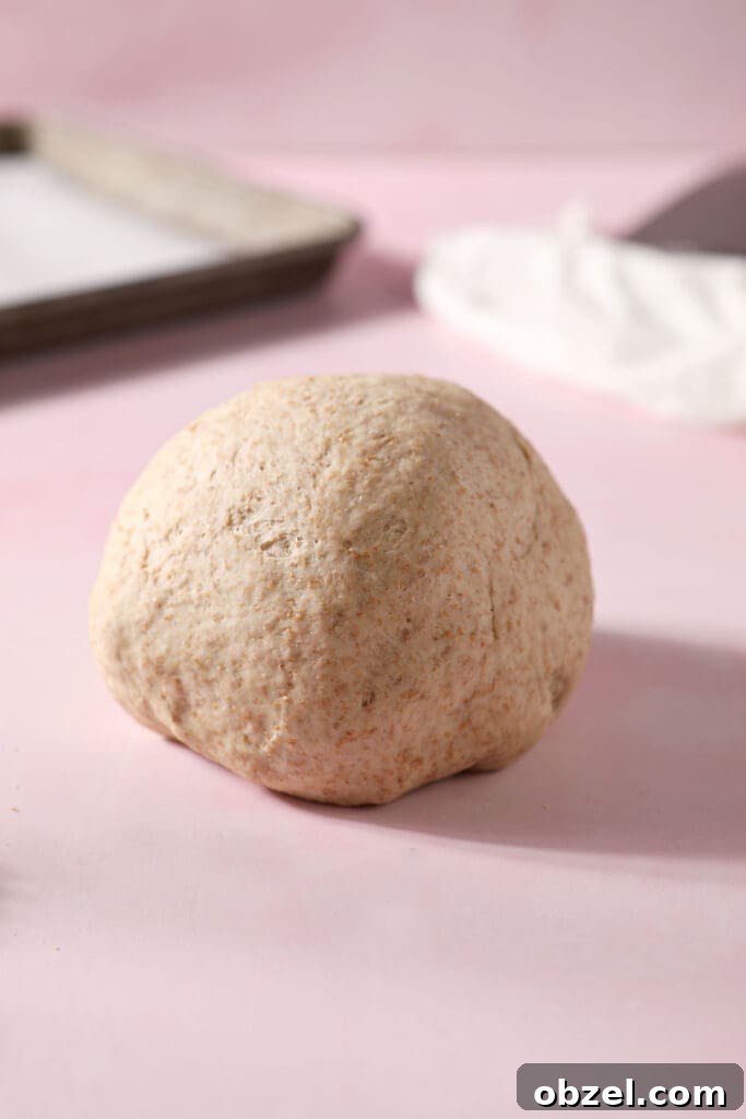 A round of pizza dough on a pink surface