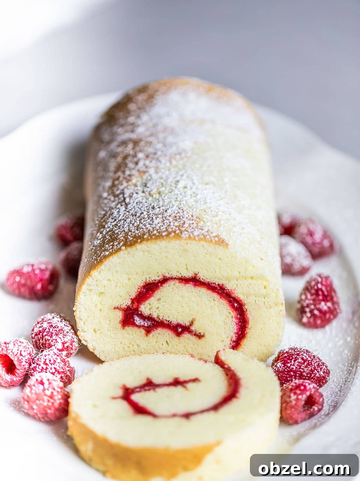 Bakery Style Swiss Roll Cake Recipe 2 Swiss roll cake with raspberries on white plate.