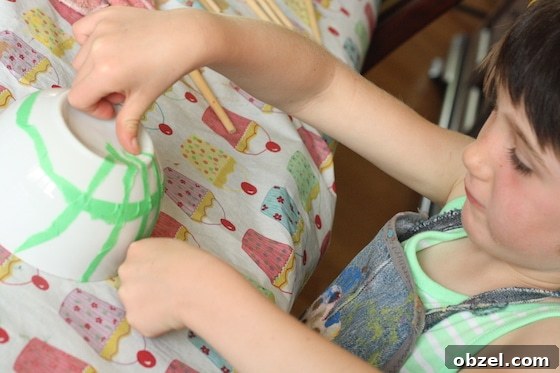Child putting painter's tape on a white bowl
