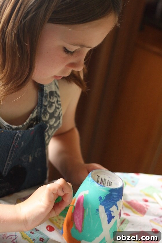 child removing painters tape from painted mug