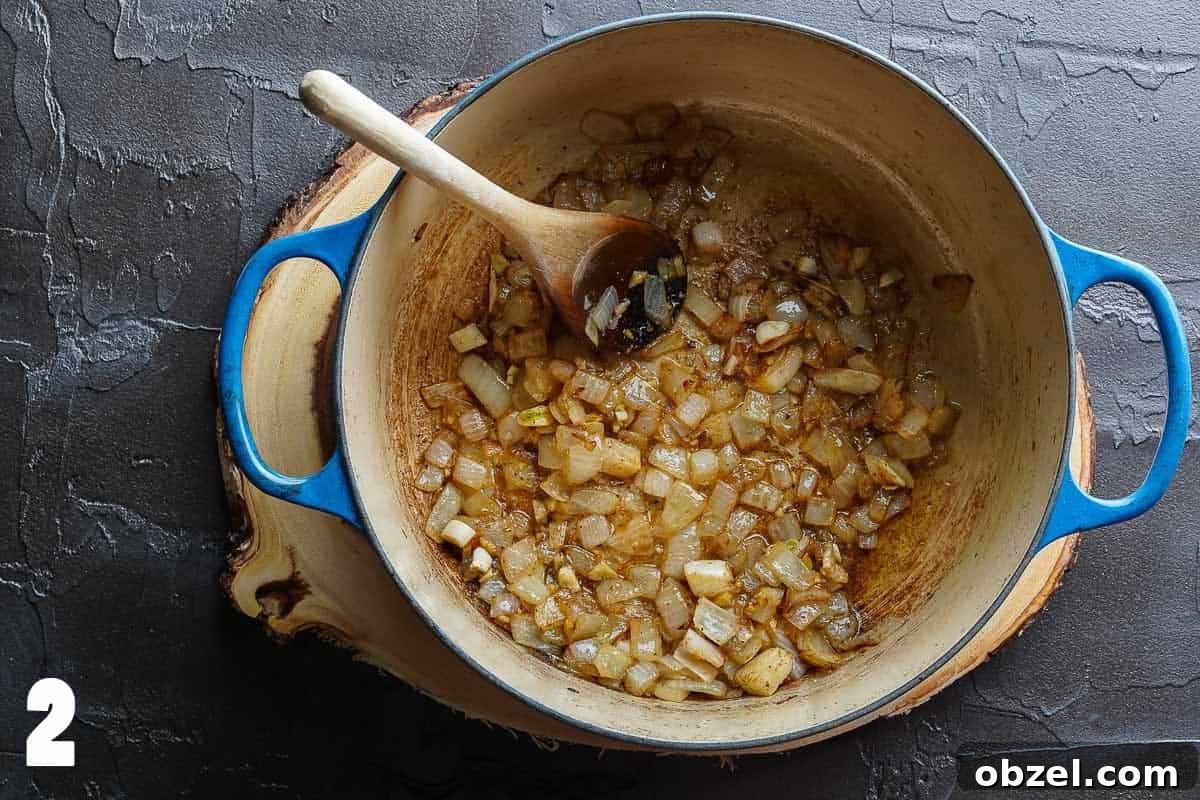 Velvety Carrot, Pumpkin and Apple Soup Recipe 5 Onions garlic and spices browned in blue pot with wooden spoon