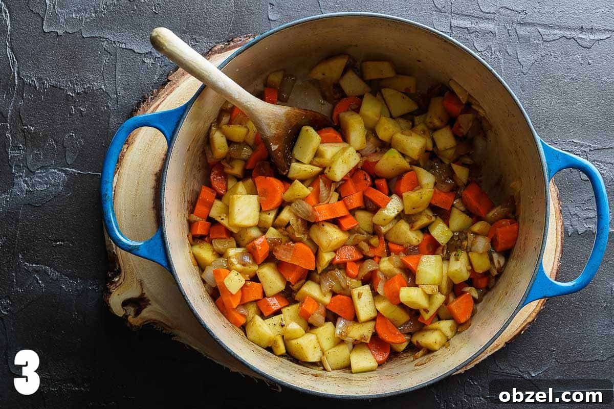 Velvety Carrot, Pumpkin and Apple Soup Recipe 6 chopped apples carrots and onions in blue pot with wooden spoon