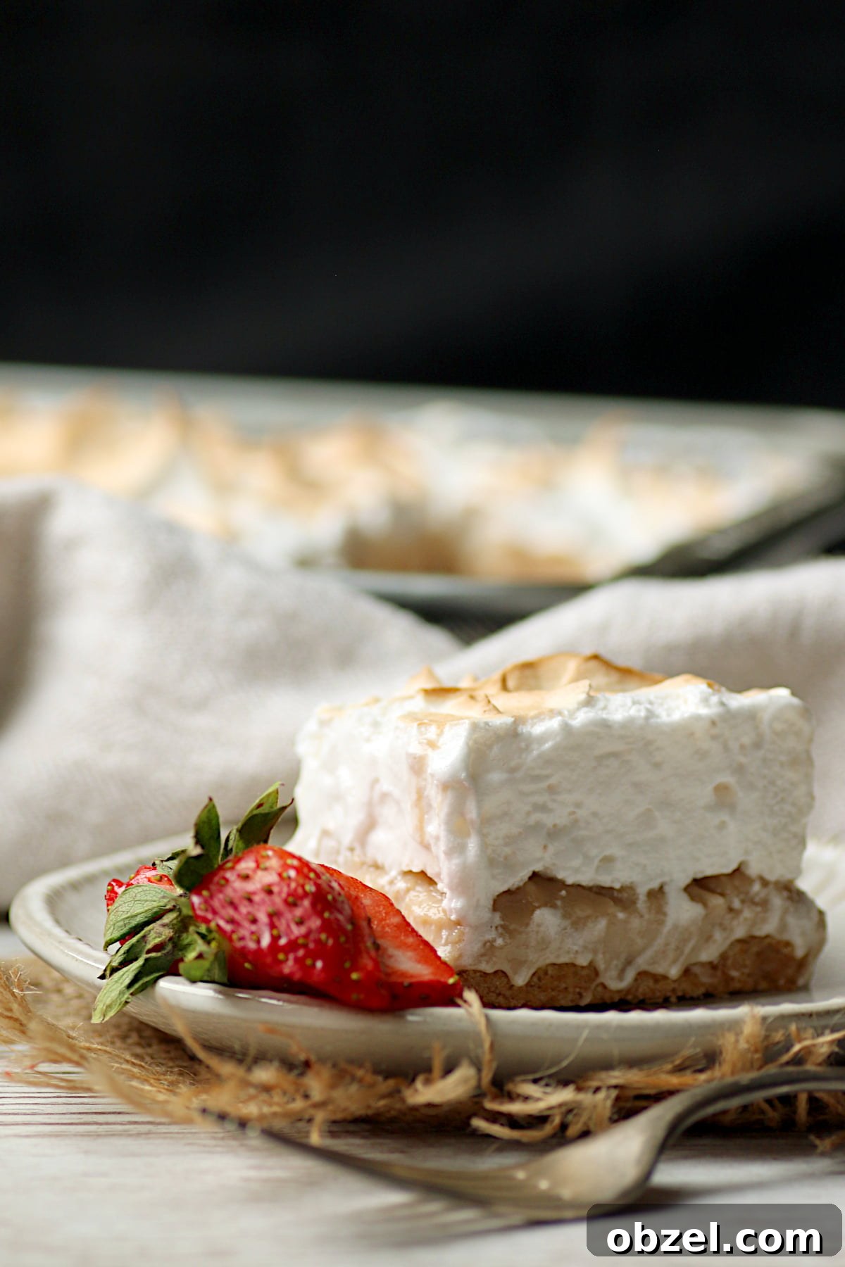 Strawberry Rhubarb Meringue Bars Recipe 4 Closeup photo of a Strawberry Rhubarb Meringue Square on a small white plate.