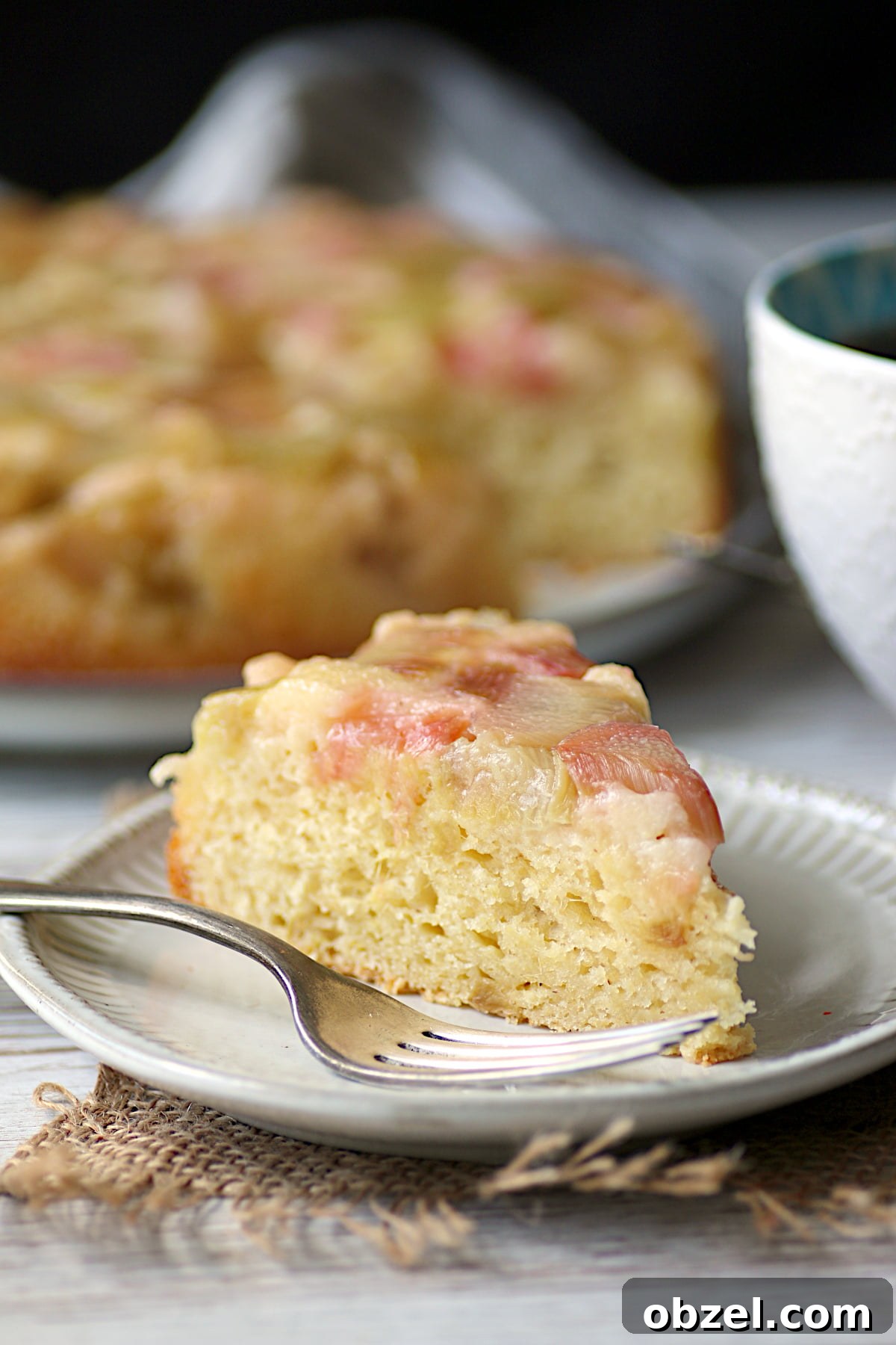 Strawberry Rhubarb Meringue Bars Recipe 5 A slice of Cornmeal Rhubarb Upside-Down Cake on a small, white plate.