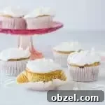 Gluten-Free Coconut Cupcakes with Fluffy Frosting 7 gluten-free coconut cupcakes with coconut sprinkled around them
