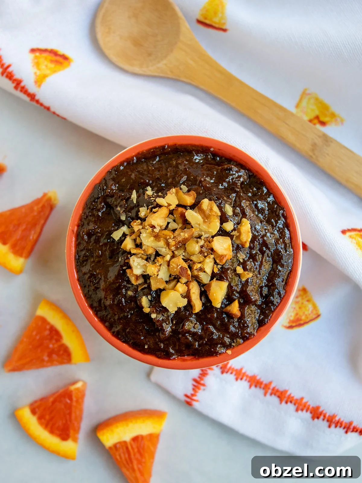 How to Make Lekvar Prune Butter at Home 2 Bowl of lekvar prune butter in an orange bowl with a wooden spoon and triangular orange pieces.