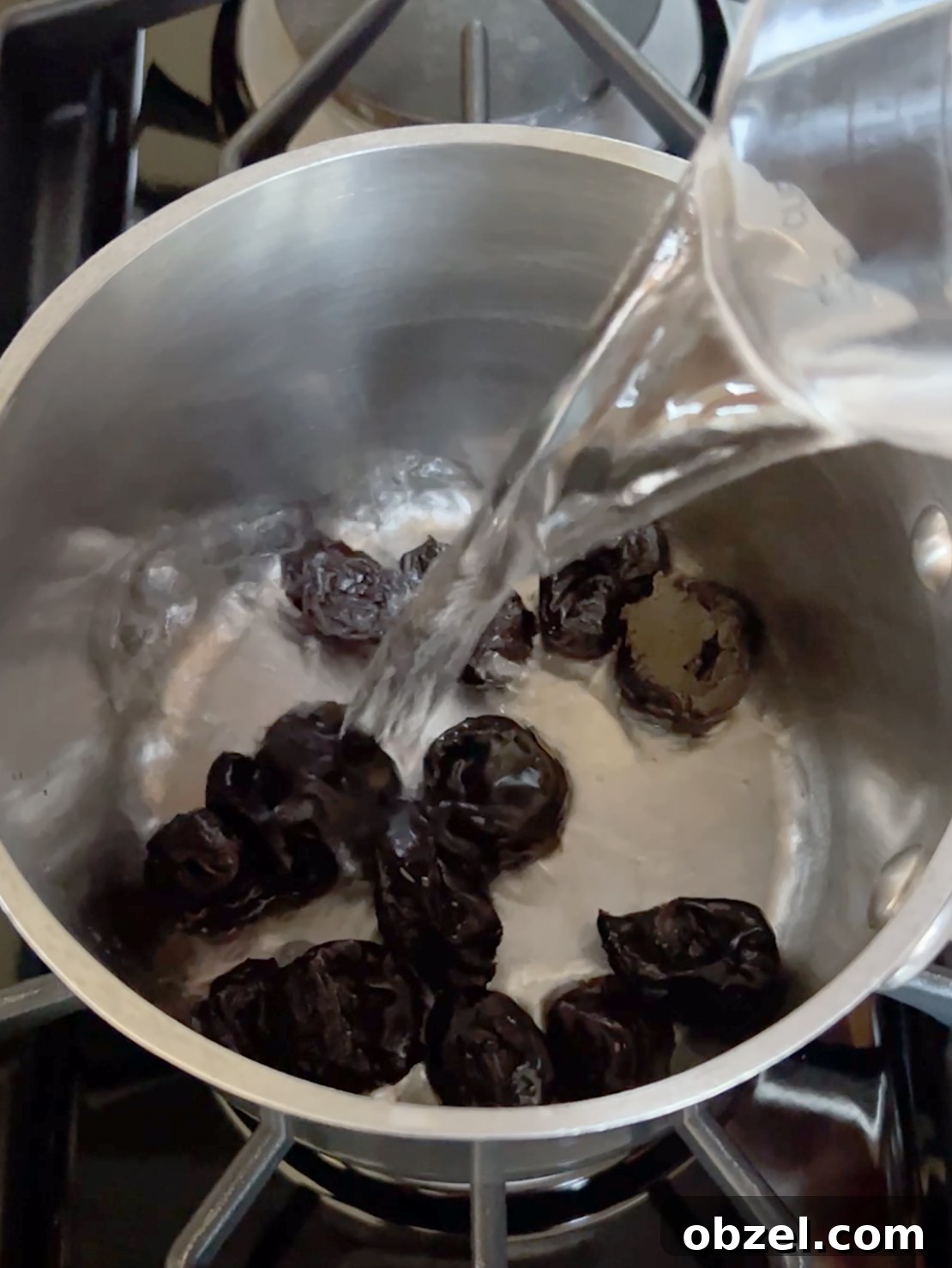 How to Make Lekvar Prune Butter at Home 4 Prunes in a pot with water being poured over them.