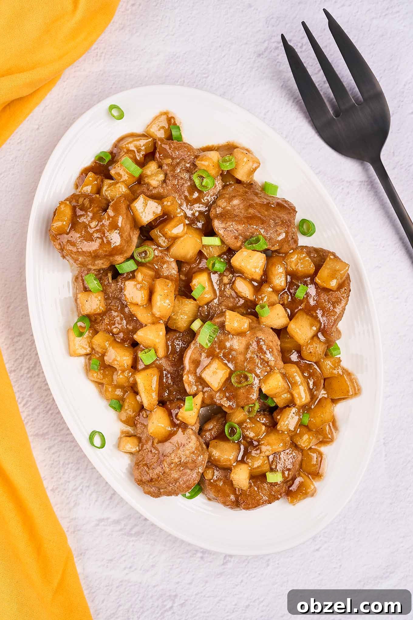 Caribbean Pineapple Pork Skillet with Bell Peppers 2 An oval serving platter of Caribbean-style pineapple pork with tender pork medallions, pineapple chunks, and scallions in a sweet-savory rum sauce.