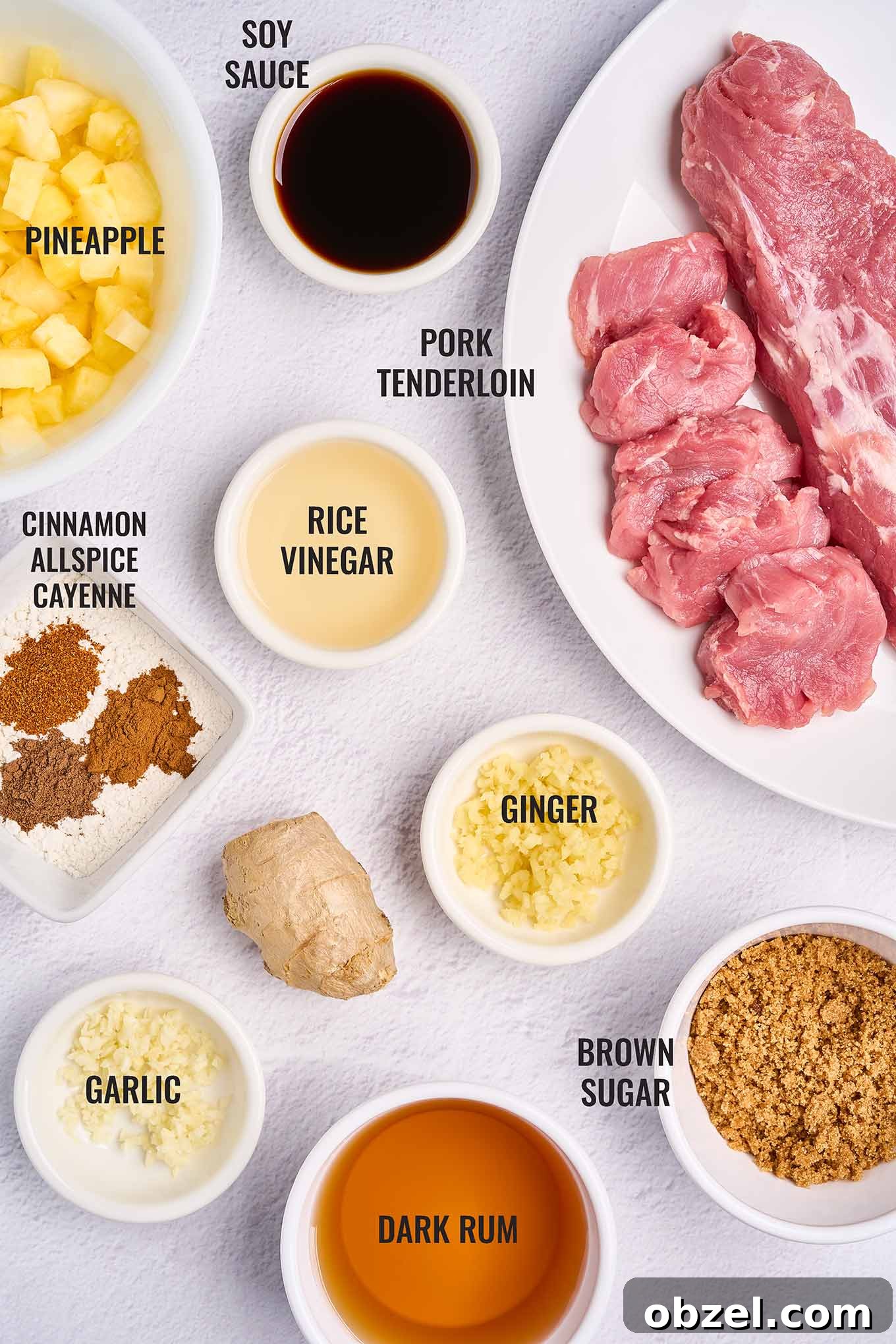 Caribbean Pineapple Pork Skillet with Bell Peppers 3 A labeled overhead view of the ingredients for Caribbean pineapple pork with rum sauce, including pork tenderloin, pineapple, rum, brown sugar, and spices.