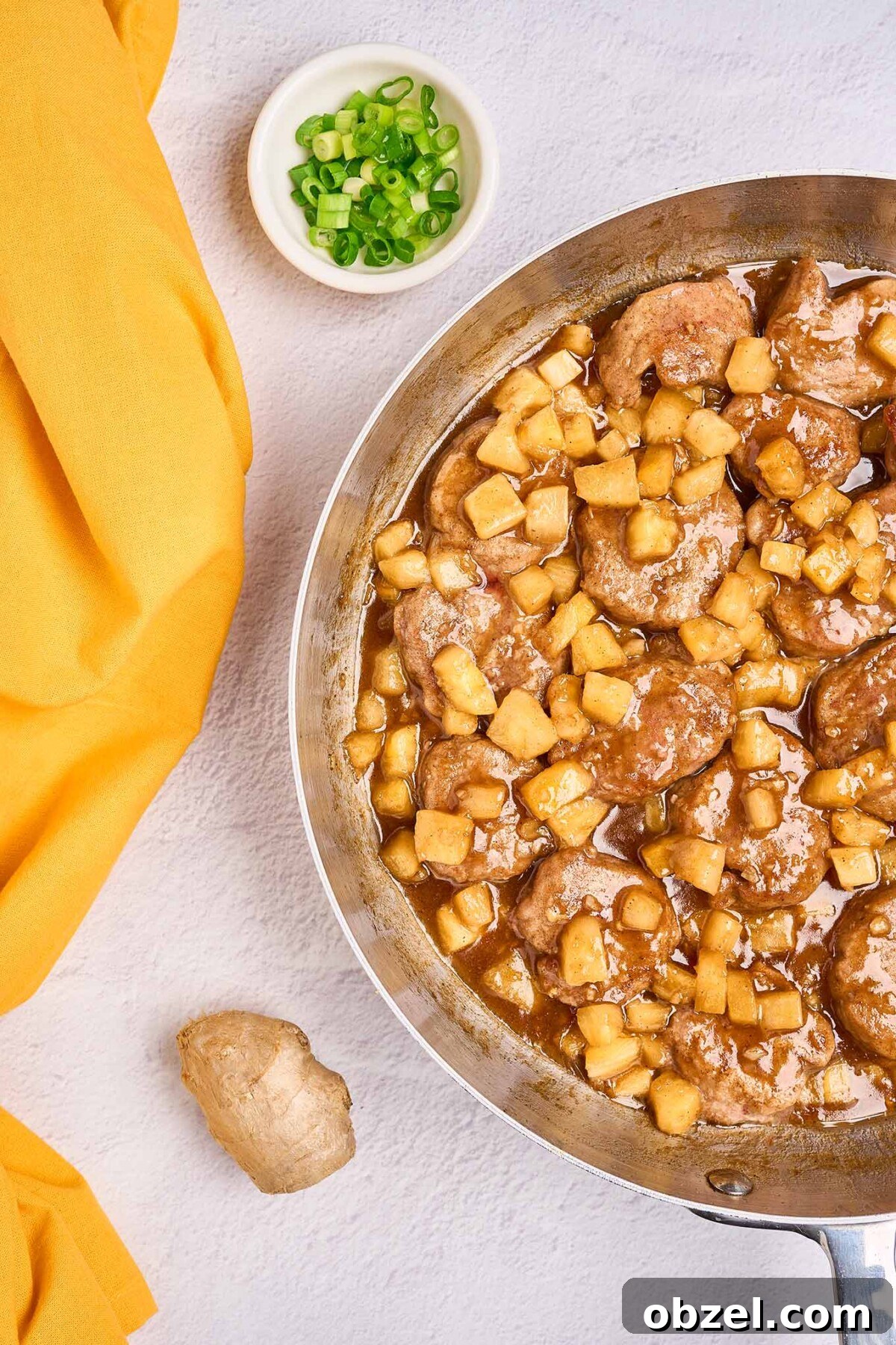 Caribbean Pineapple Pork Skillet with Bell Peppers 4 A skillet filled with tender pork medallions, and pineapple chunks in a sweet-savory rum sauce, a small bowl of chopped scallions and a knob of ginger to the side.