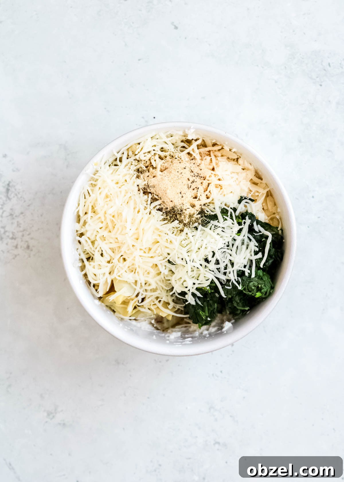 Creamy Spinach Artichoke Dip Recipe 6 spinach, cheese, seasonings, chopped artichokes in a bowl with cream cheese, mayonnaise, and yogurt in a white bowl