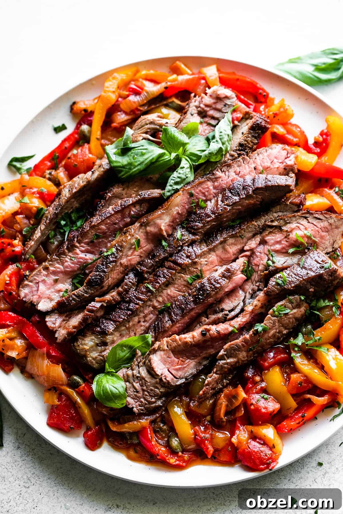 Slices of grilled flank steak served over a bed of peperonata.