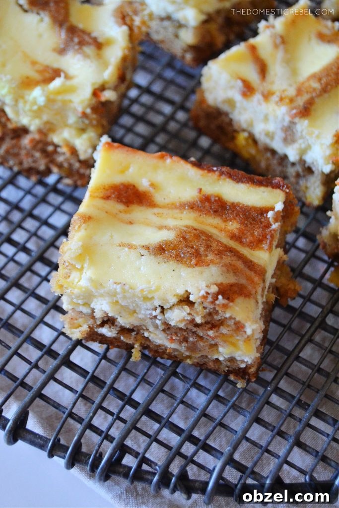 Carrot Cake Cheesecake Bars Recipe 3 an aerial shot of a carrot cake cheesecake bar sitting on a black cooling back.