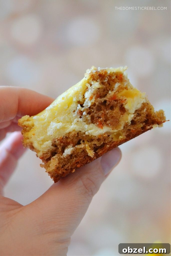 Carrot Cake Cheesecake Bars Recipe 6 author holding a slice of carrot cake cheesecake bars against a light spotted background
