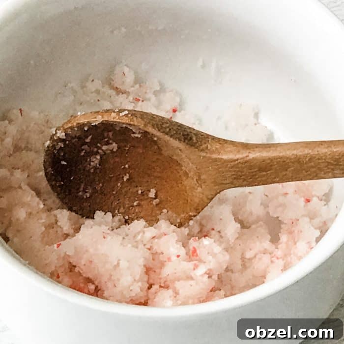 DIY Peppermint Candy Cane Lip Scrub for Soft Lips 10 peppermint candy cane lip scrub with essential oils ingredients sugar, candy cane pieces, peppermint essential oil, apricot kernel oil mixed together with wooden spoon