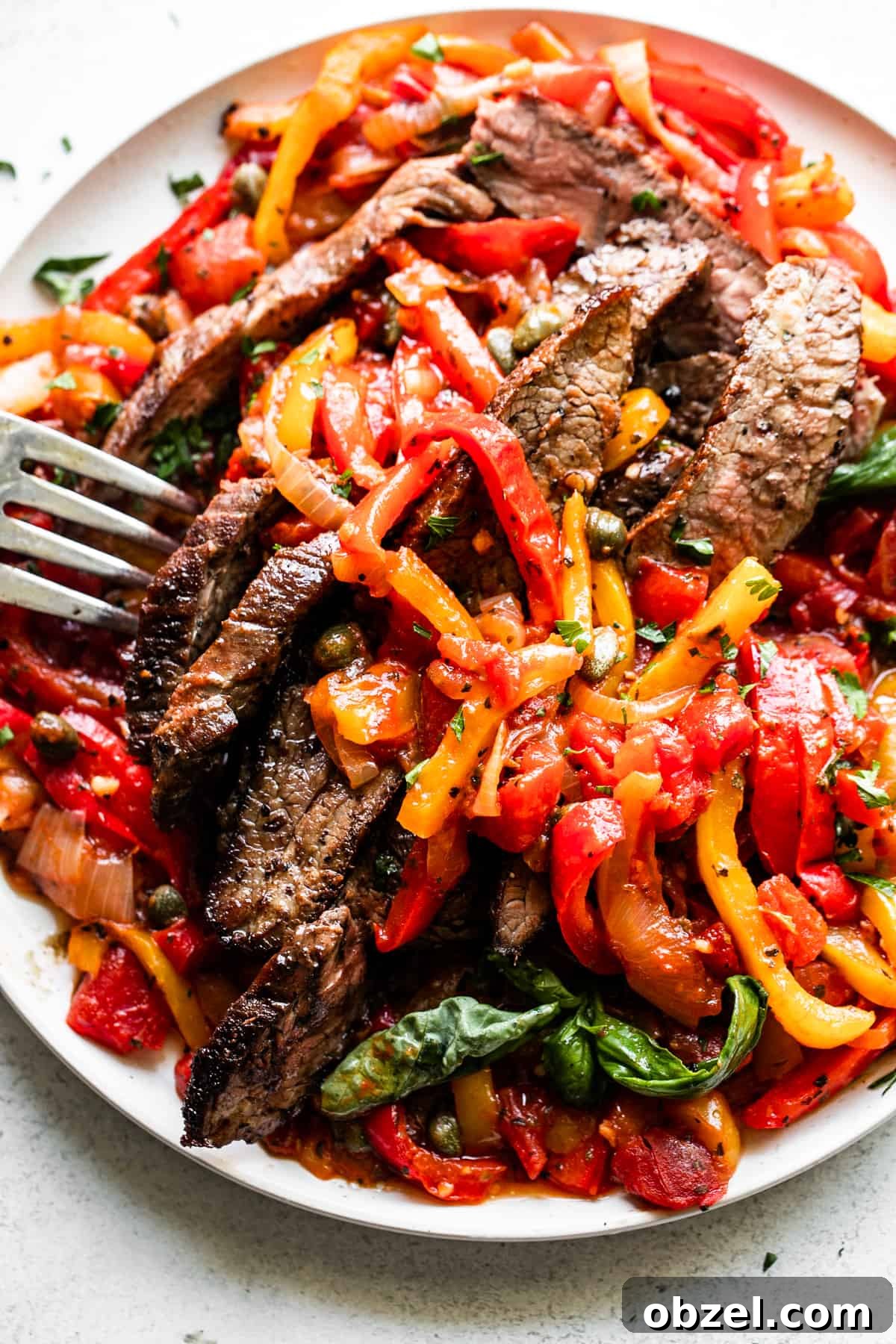 overhead shot of flank steak peperonata served in a round plate