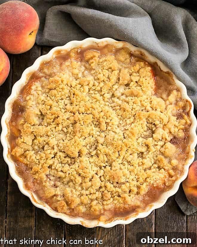 Classic Peach Crisp - Sweetened peaches with a buttery, brown sugar crisp topping for the ultimate summer dessert Overhead view of a Classic Peach Crisp in a white ceramic dish