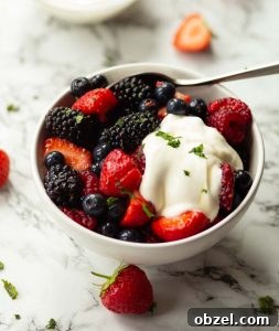 Berry Fruit Salad berry fruit salad served in small white bowl with silver spoon garnished with yogurt and mint