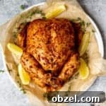 Traeger Smoked Whole Chicken Recipe 12 Whole smoked chicken on a serving platter with lemon wedges and parsley.