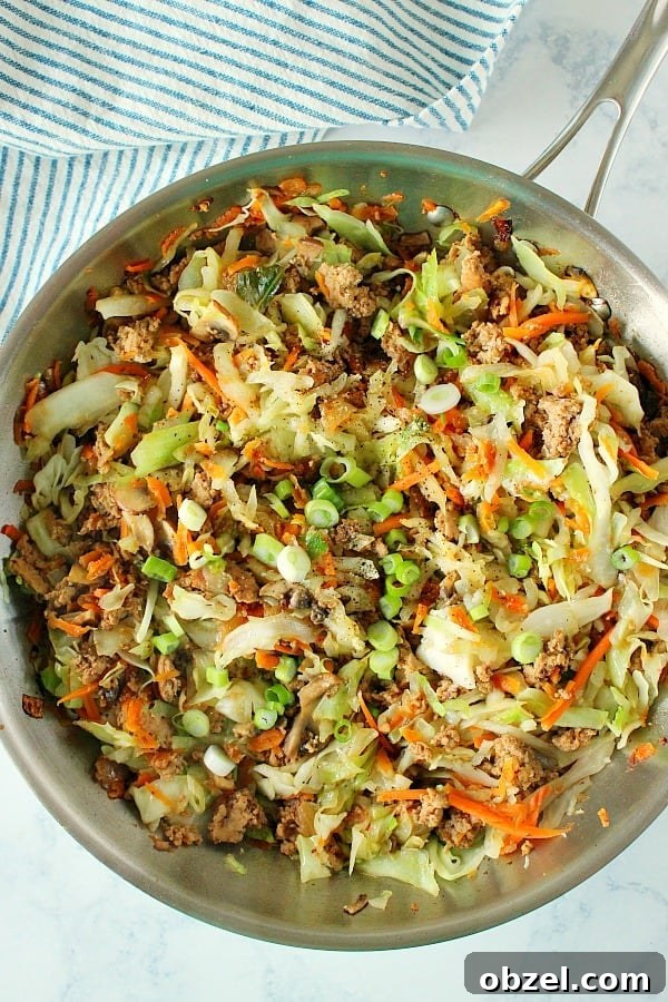 Egg Roll in a Bowl - quick and easy low-carb dinner made with ground chicken, pork or turkey, coleslaw mix, more veggies and Asian sauce. Overhead shot of egg roll filling in skillet.