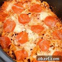 Crock Pot Pizza Casserole with Pasta and Pepperoni 8 A close up of a slow cooker filled with pizza casserole, topped with pepperoni.