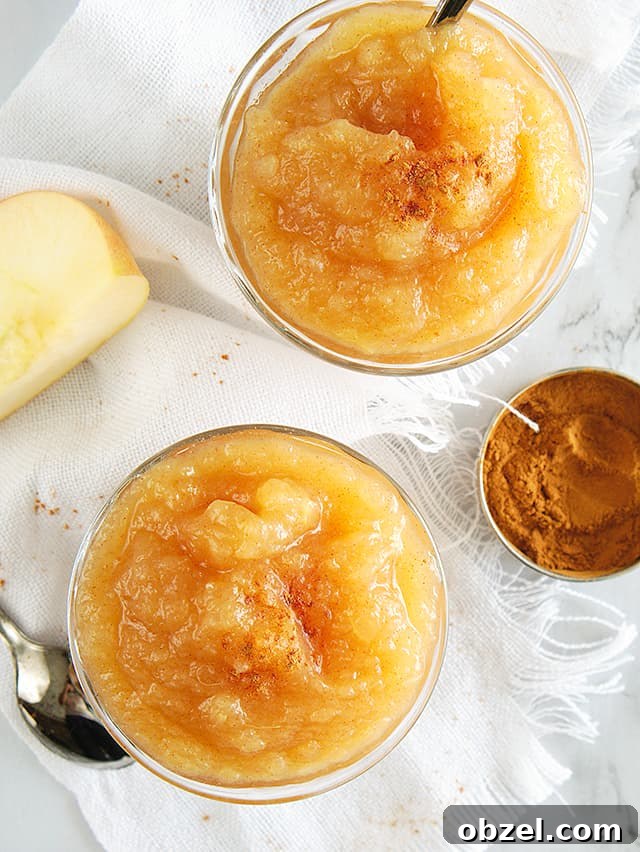two small bowls of instant pot applesauce with ground cinnamon, apple slice, and white linen