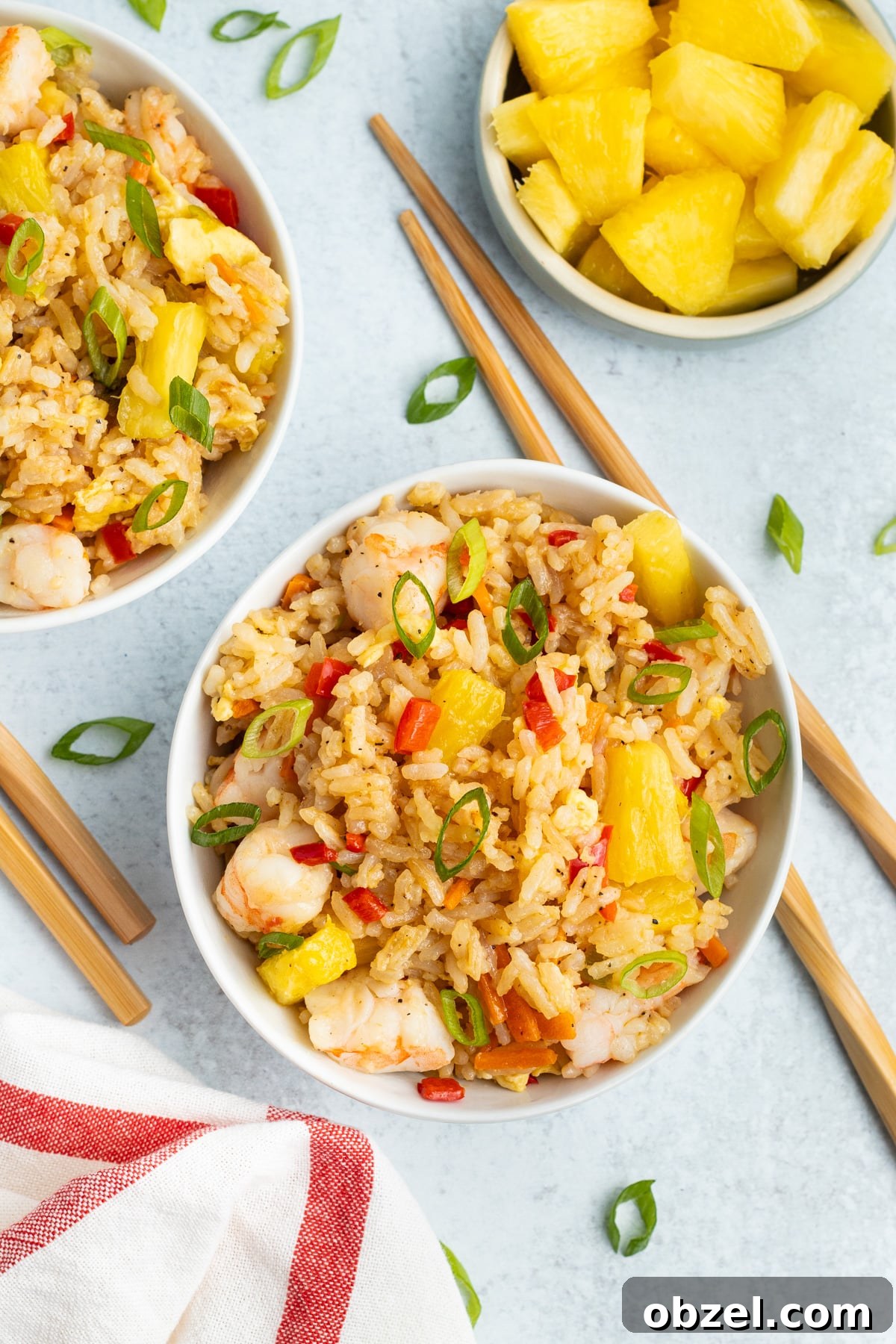 Pineapple Shrimp Fried Rice Recipe 3 Two bowls filled with shrimp pineapple fried rice with pineapple and chopsticks nearby.