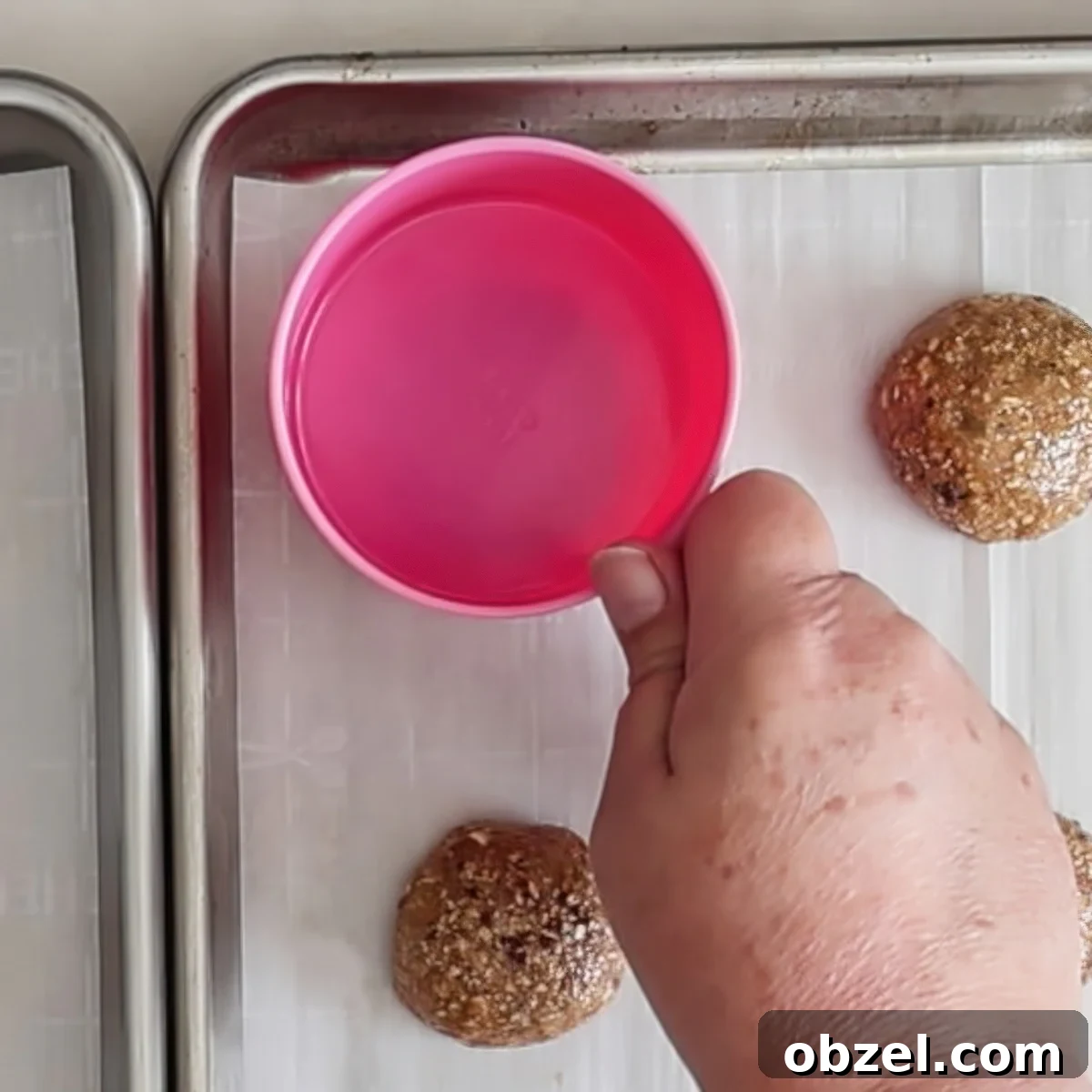 pressing hot pink measuring cup on top of cookie dough.