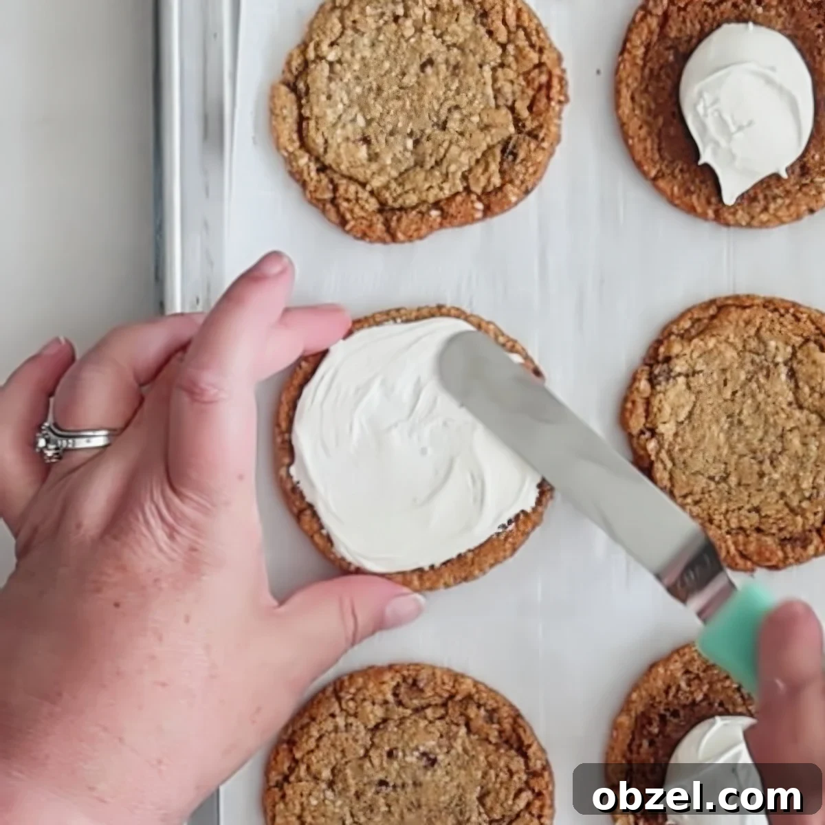 spreading white frosting onto cookie.