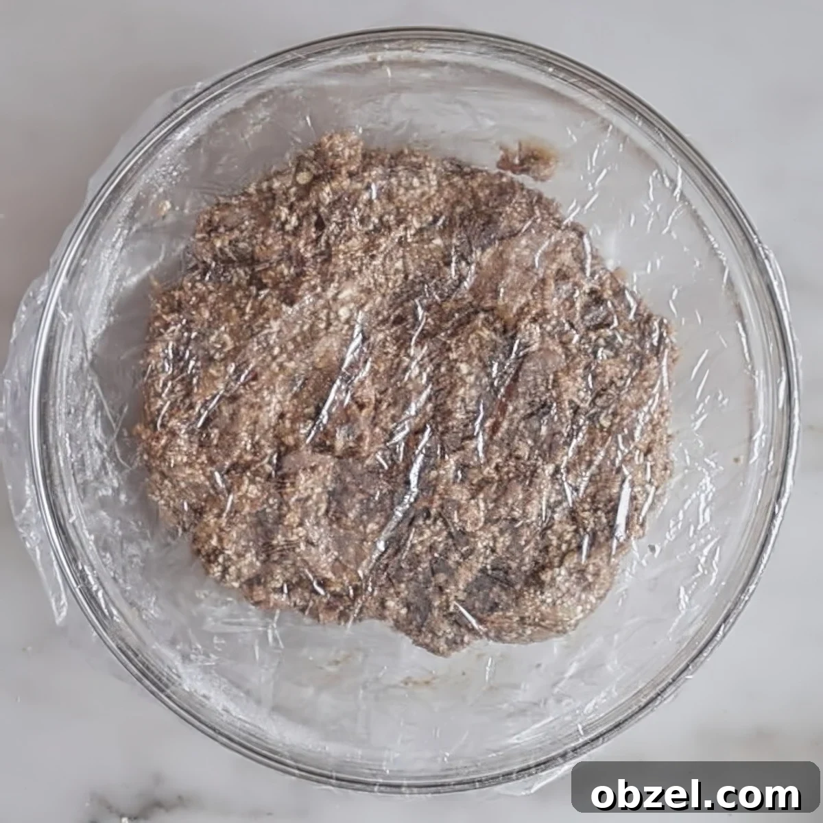 oatmeal cookie dough in covered glass bowl.