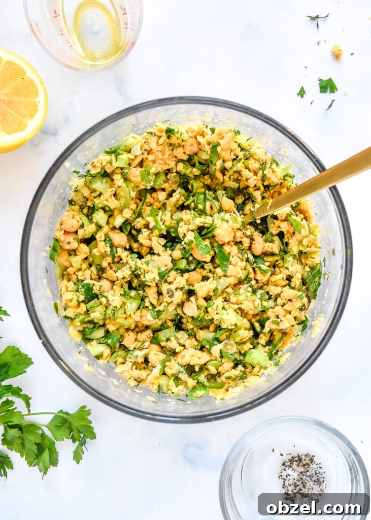 Lemony Herbed Mashed Chickpea Salad Recipe 10 finished herby lemon mashed chickpea salad in a glass bowl with fresh herbs and lemon juice.