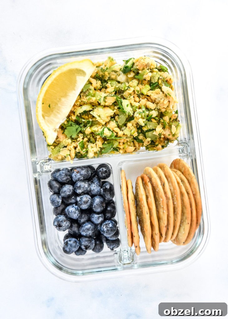 Lemony Herbed Mashed Chickpea Salad Recipe 15 herby lemon mashed chickpea salad in a glass meal prep container with blueberries and crackers.