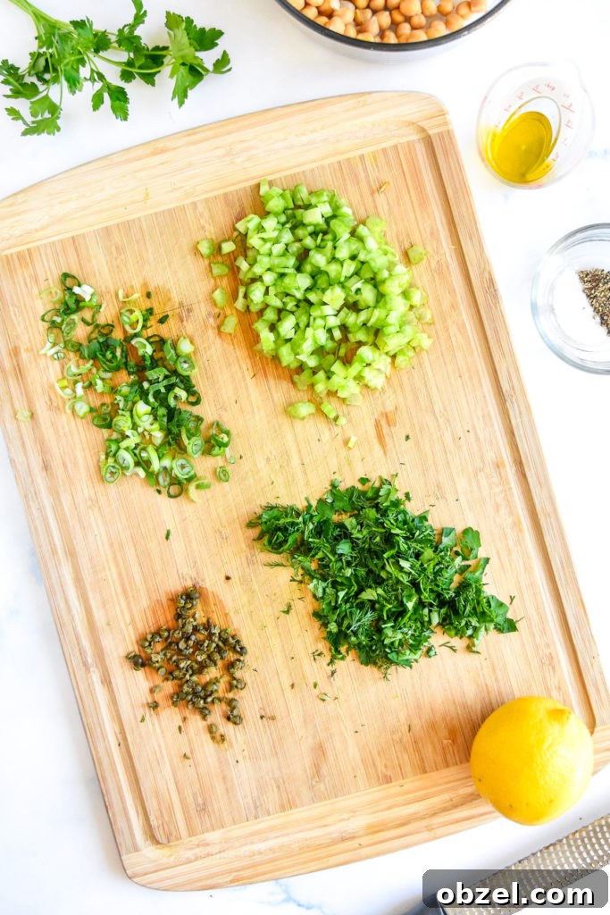 Lemony Herbed Mashed Chickpea Salad Recipe 6 chopped greens and capers on a bamboo cutting board.