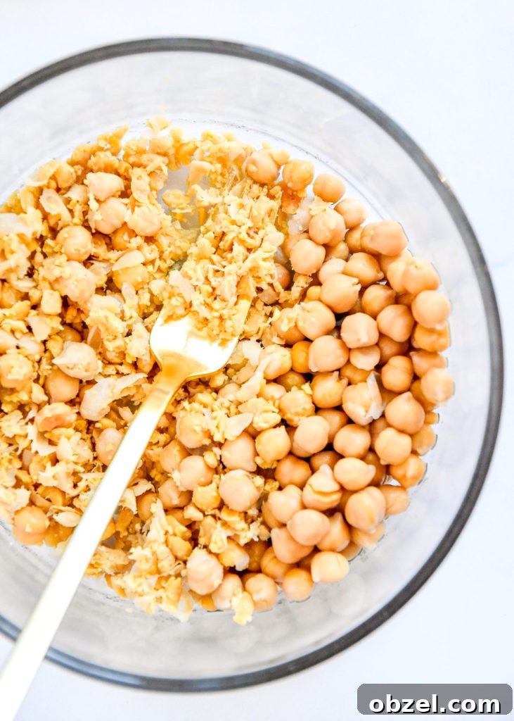 Lemony Herbed Mashed Chickpea Salad Recipe 7 mashing chickpeas in a bowl with a fork.