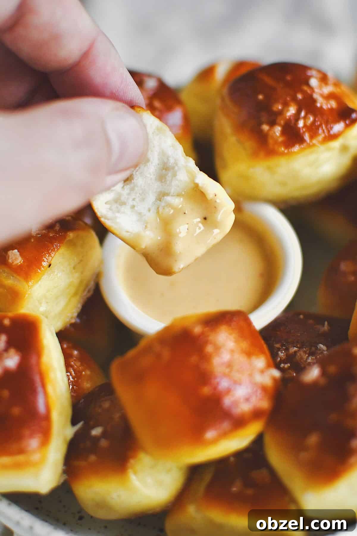 Dipping a split pretzel bite into cheese sauce before eating.