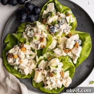 Chicken Waldorf Salad Recipe with Apples and Grapes 8 Overhead picture of salad in lettuce leaves on a plate. A bunch of grapes in the corner and a light colored napkin to the side.