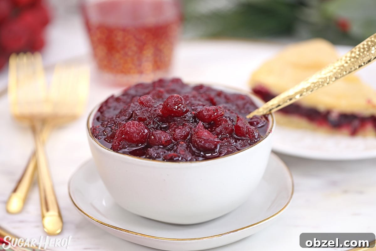 Cranberry Orange Sauce Recipe 13 Homemade cranberry sauce in a white bowl with a gold spoon and cranberry cake in the background.