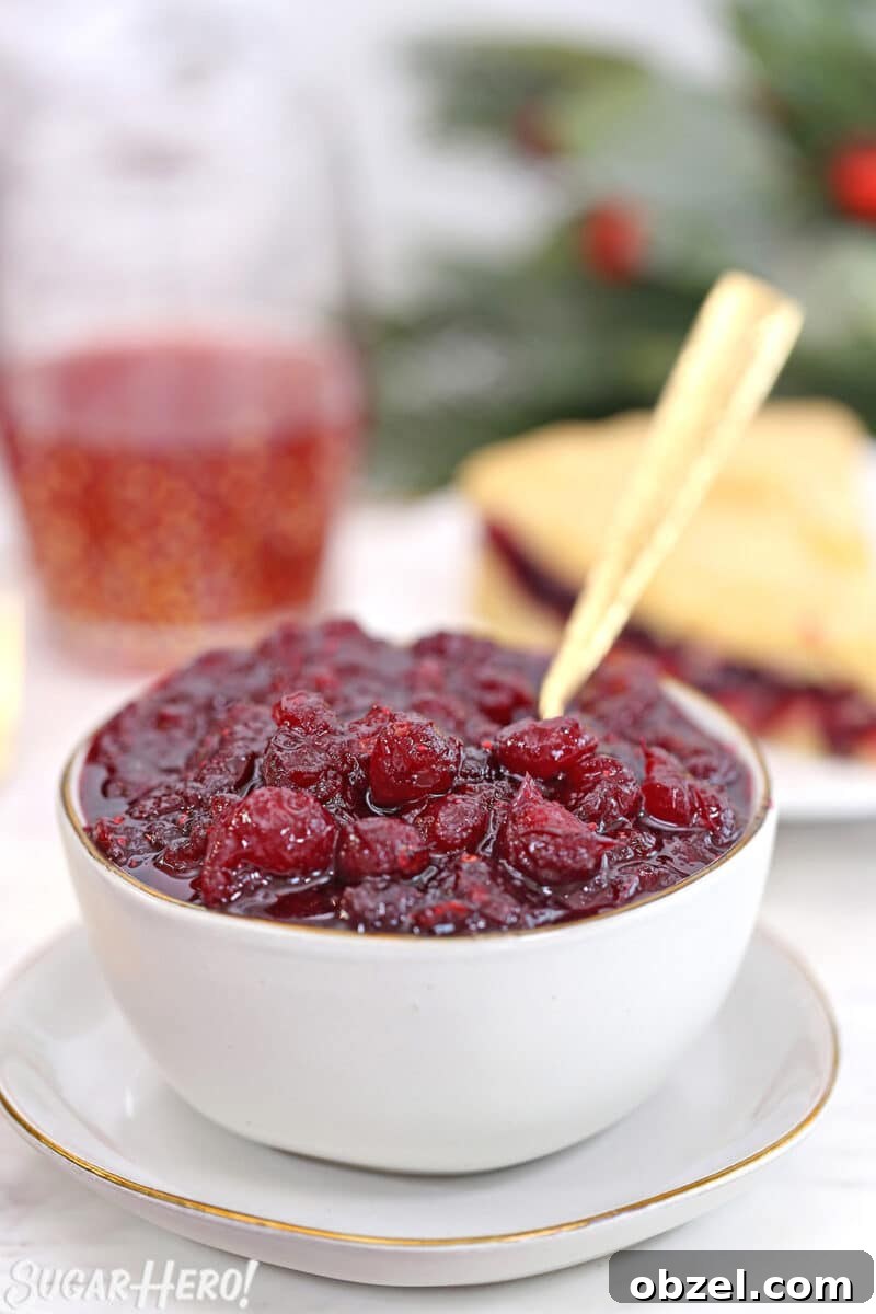 Cranberry Orange Sauce Recipe 15 Homemade cranberry sauce in a white bowl with a gold spoon sticking out.