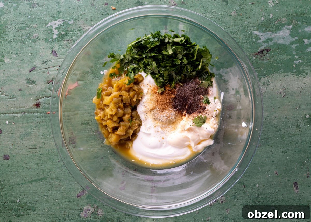 Creamy Green Chile Cilantro Dip 4 overhead of unmixed green chile cilantro dip in a glass bowl on a green surface