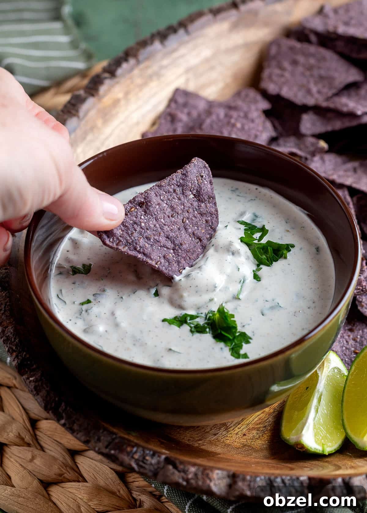 Creamy Green Chile Cilantro Dip 7 a blue corn tortilla chip being dipped into a bowl of green chile cilantro dip
