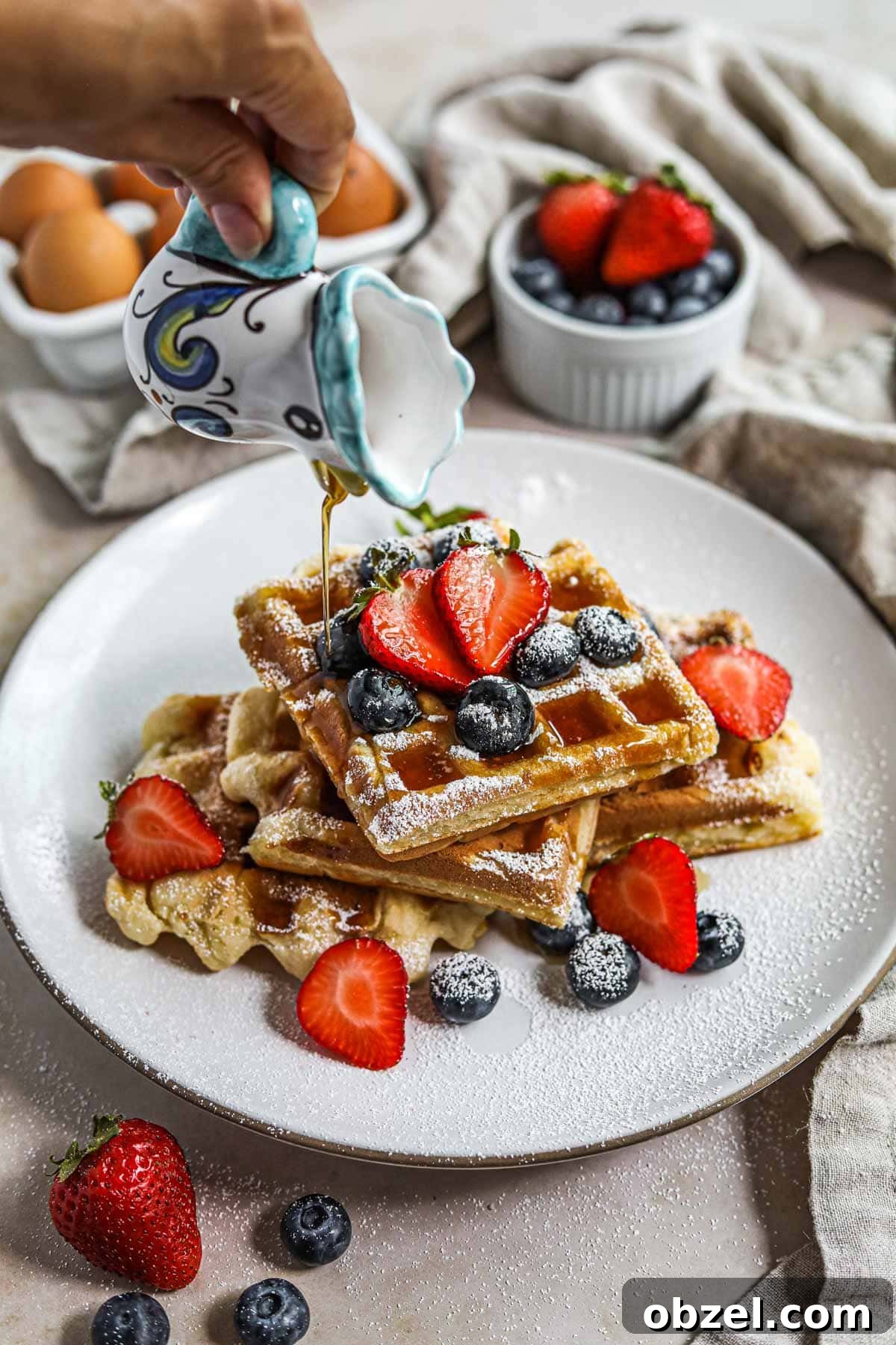 Gluten Free Mochi Waffles with Crispy Chewy Texture 6 Hand pouring maple syrup on top of mochi waffles on a plate.