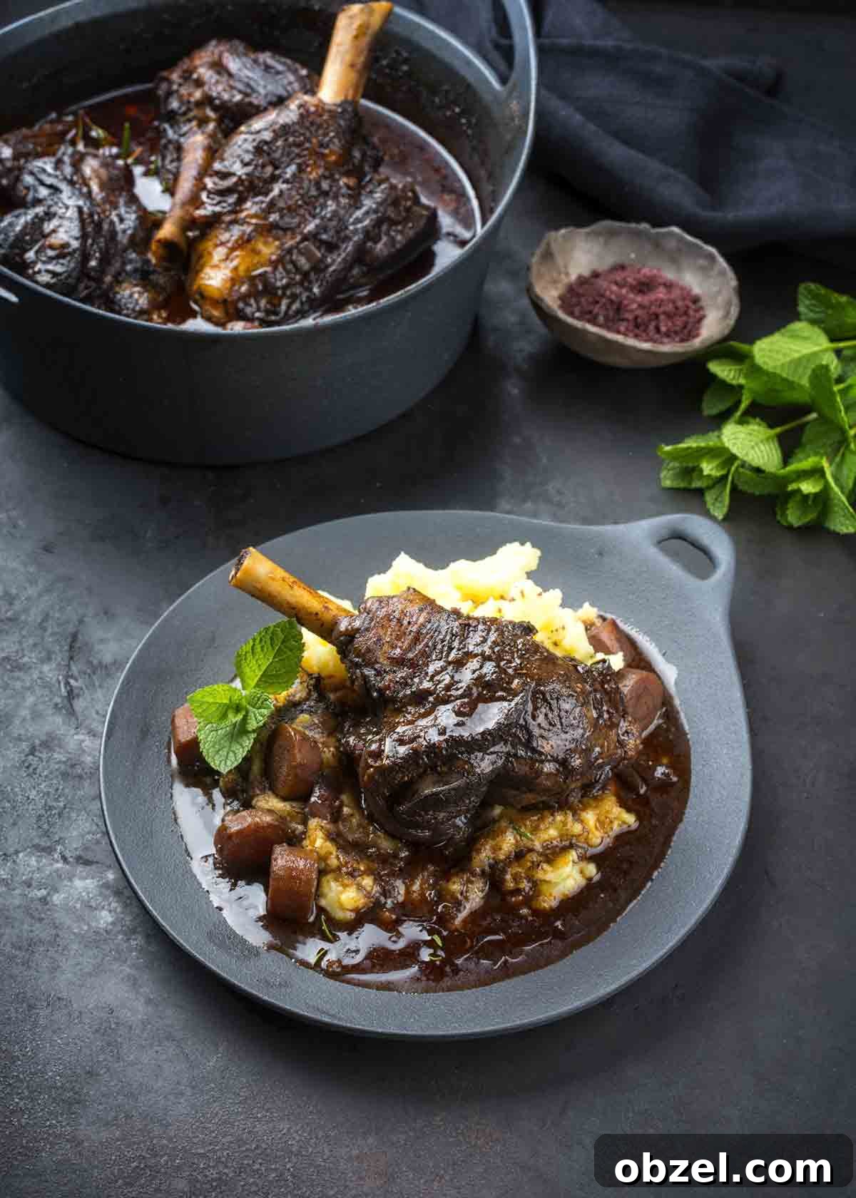 What Is Braising? Cooking Method, Tips, and Uses 2 A grey plate topped with braised lamb, mashed potatoes, carrots, and gravy as an illustration of what is braising.