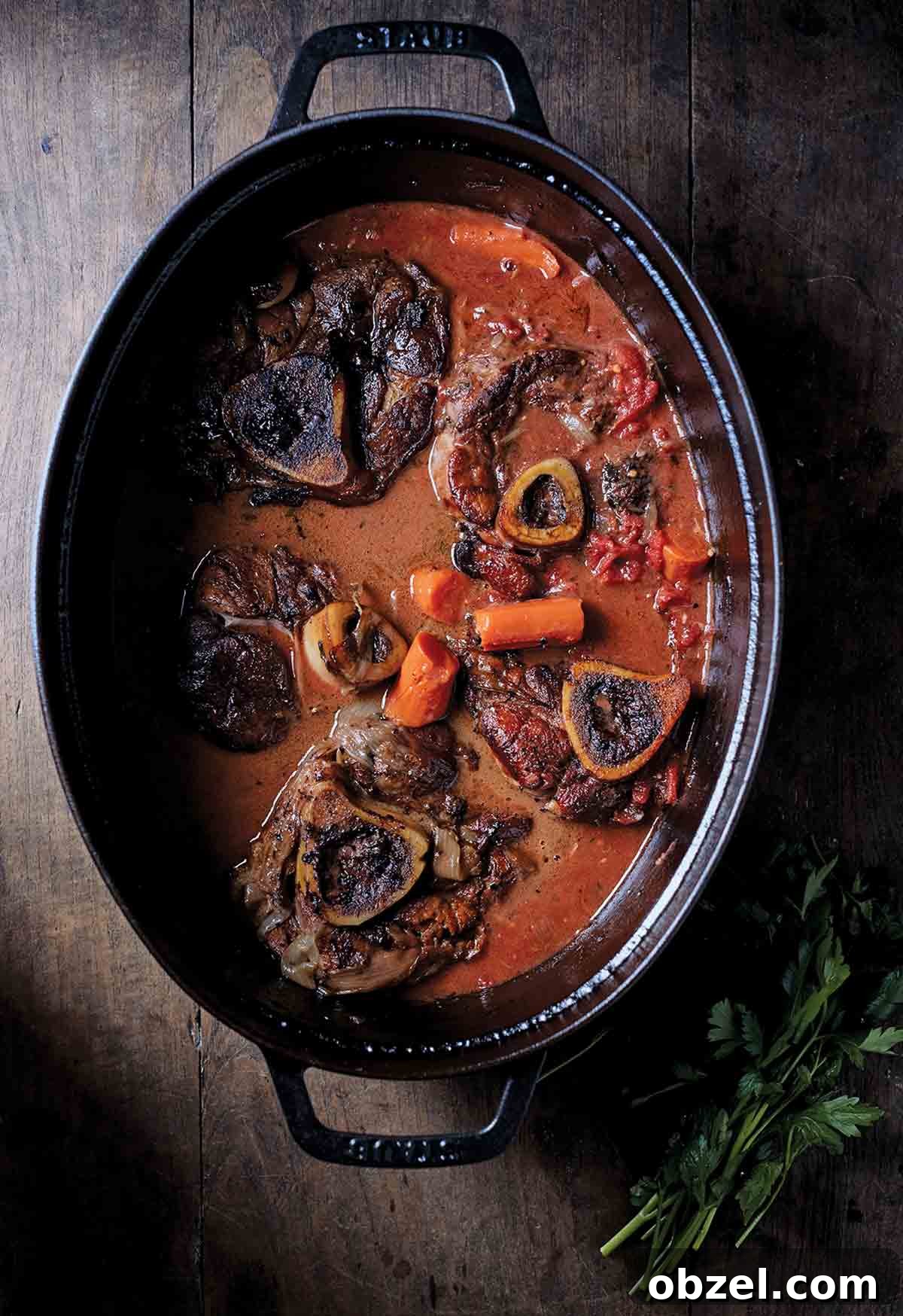 What Is Braising? Cooking Method, Tips, and Uses 3 A black oval pot with five veal osso buco pieces, carrots, and tomato sauce.