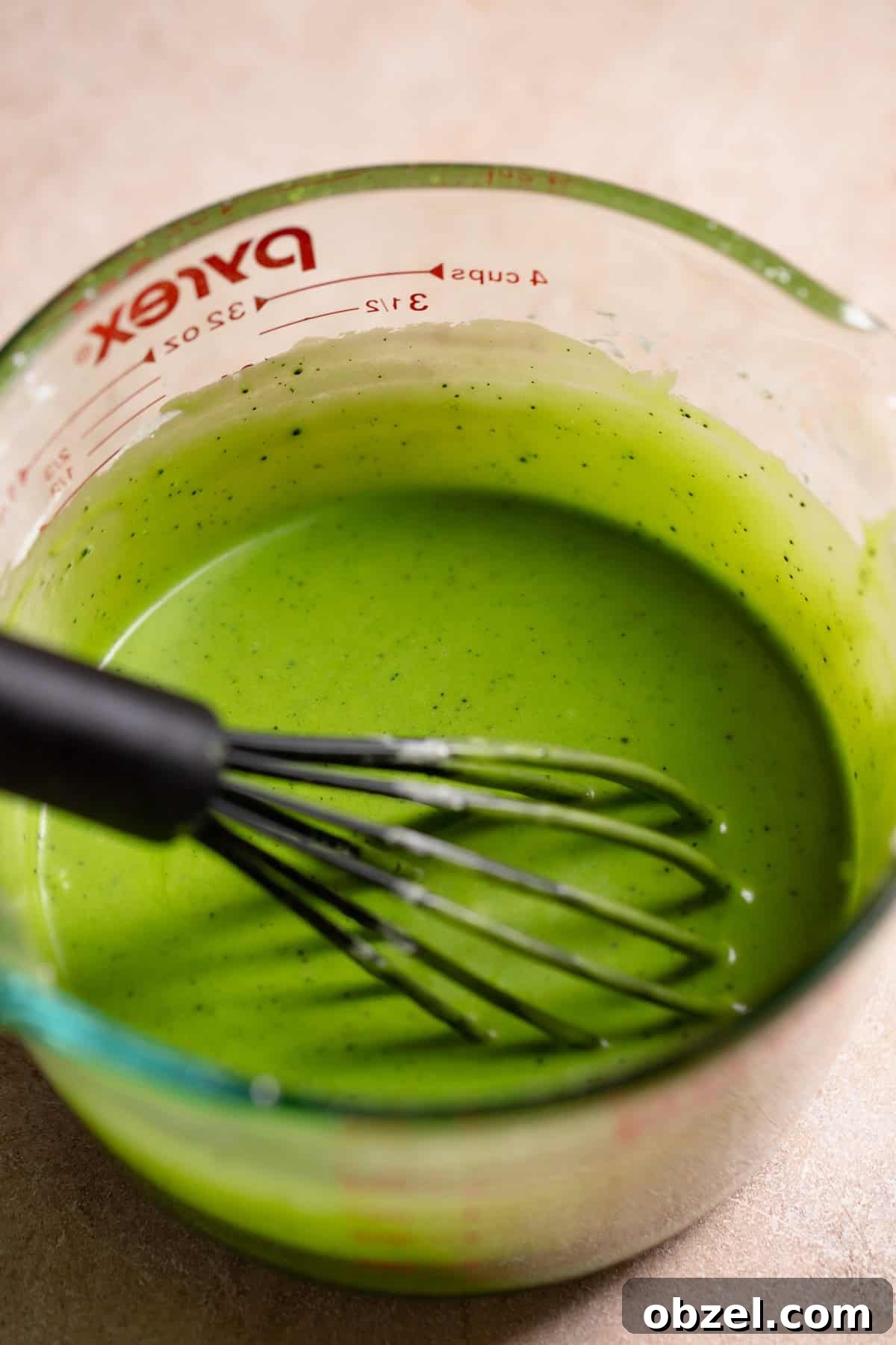 Strawberry Matcha Cinnamon Rolls Recipe 12 Matcha icing in a glass bowl with a whisk.