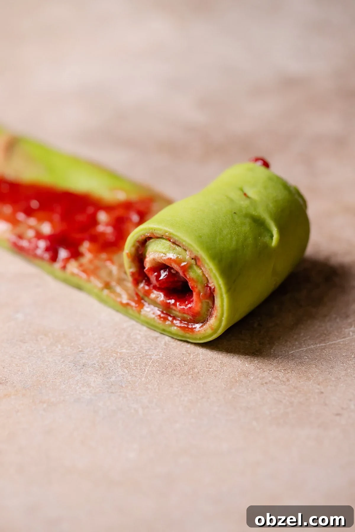 Strawberry Matcha Cinnamon Rolls Recipe 9 A strip of dough being rolled up into a cinnamon roll.
