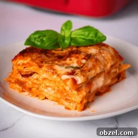 One slice of smoked Italian sausage lasagna on a white plate.