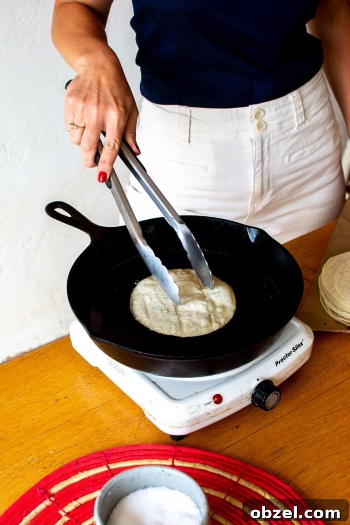 How to Make Crispy Fried Tostadas at Home 8 Pressing a tortilla with tongs while frying tostadas