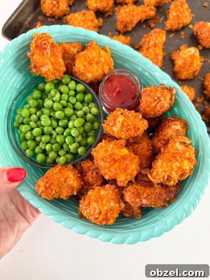 Crispy cornflake chicken nuggets served in a blue basket-style bowl with garden peas and tomato ketchup for dipping.