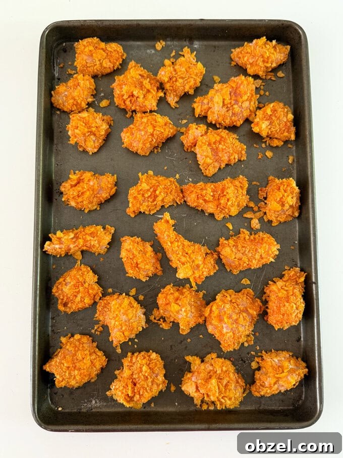Crispy cornflake chicken nuggets arranged on a baking tray.
